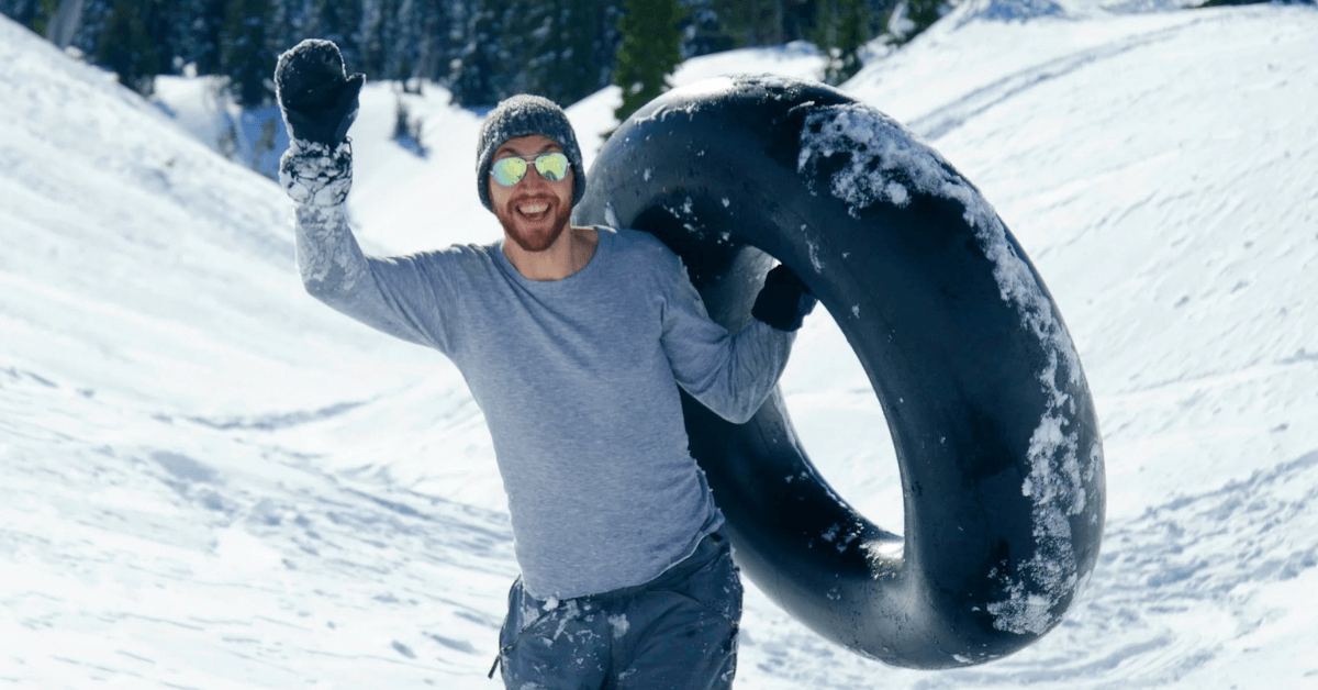 Mann mit Rodelreifen im Schnee